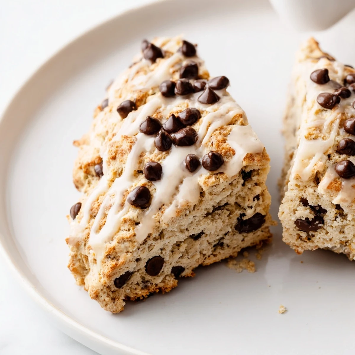 Freshly baked Chocolate Chip Scones with Glaze cooling on a wire rack, showcasing golden edges and melting chocolate chips. 