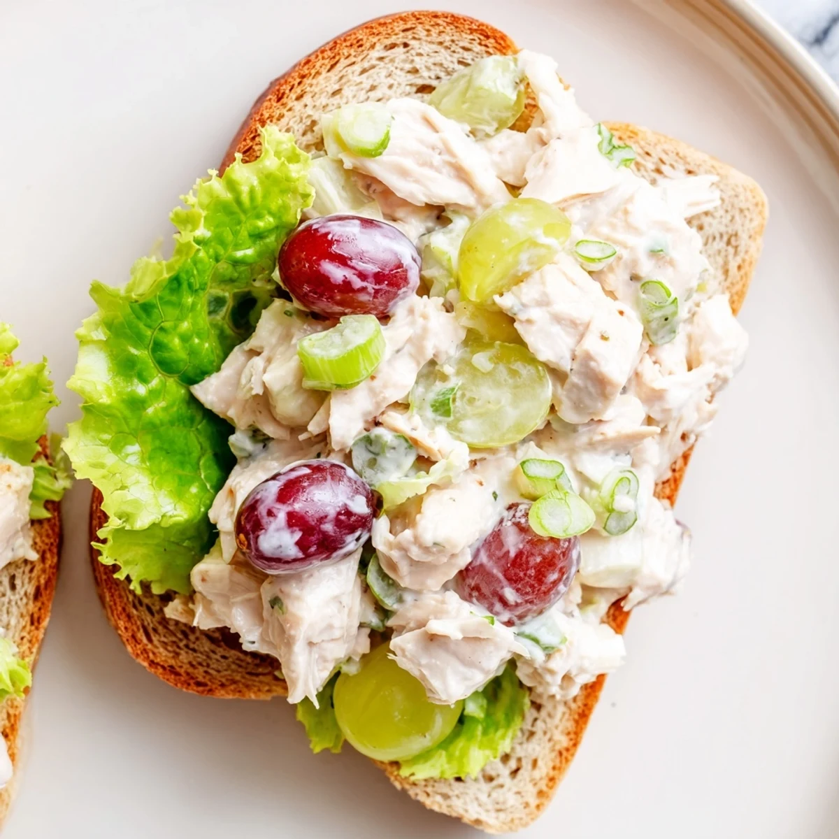An easy homemade Chicken Salad Sandwich with Grapes, piled high with colorful ingredients and served on a rustic wooden cutting board.