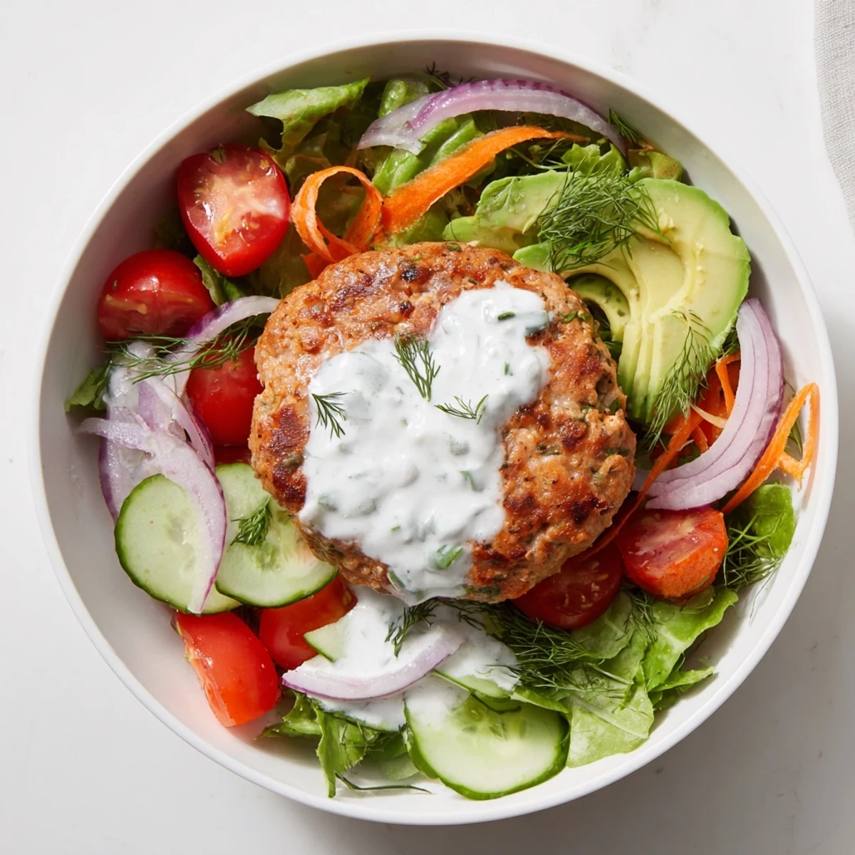 Freshly prepared turkey burger salad bowl, drizzled with tangy yogurt dressing and served with avocado.