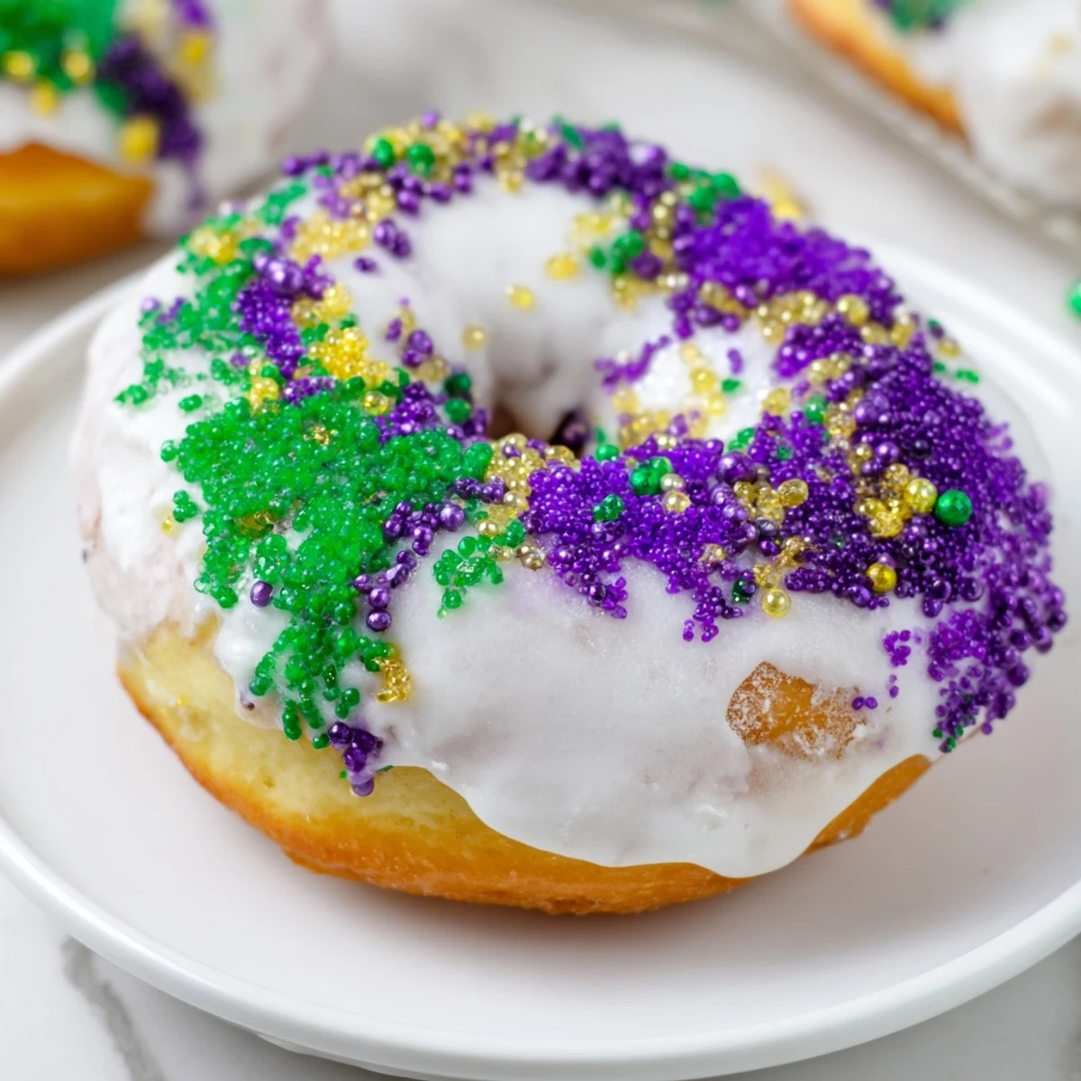 Warm Mardi Gras King Cake Donuts on a wire rack, drizzled with vanilla icing for a festive treat.  
