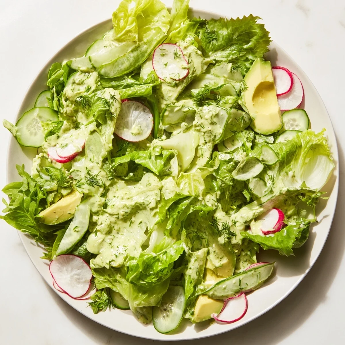 Vibrant mixed greens, cucumbers, and radishes tossed in a creamy Green Goddess dressing for a refreshing salad.