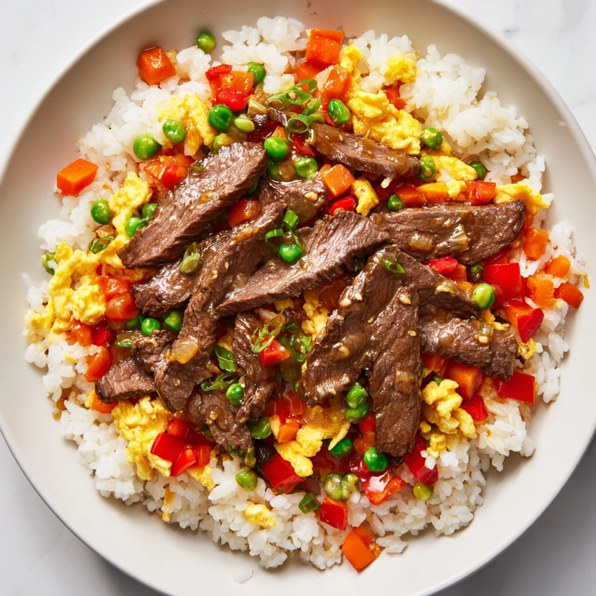 Steam rises from a colorful wok of Beef Fried Rice with Vegetables, featuring tender beef strips, scrambled eggs, and bright veggies on a serving plate ready to eat. 