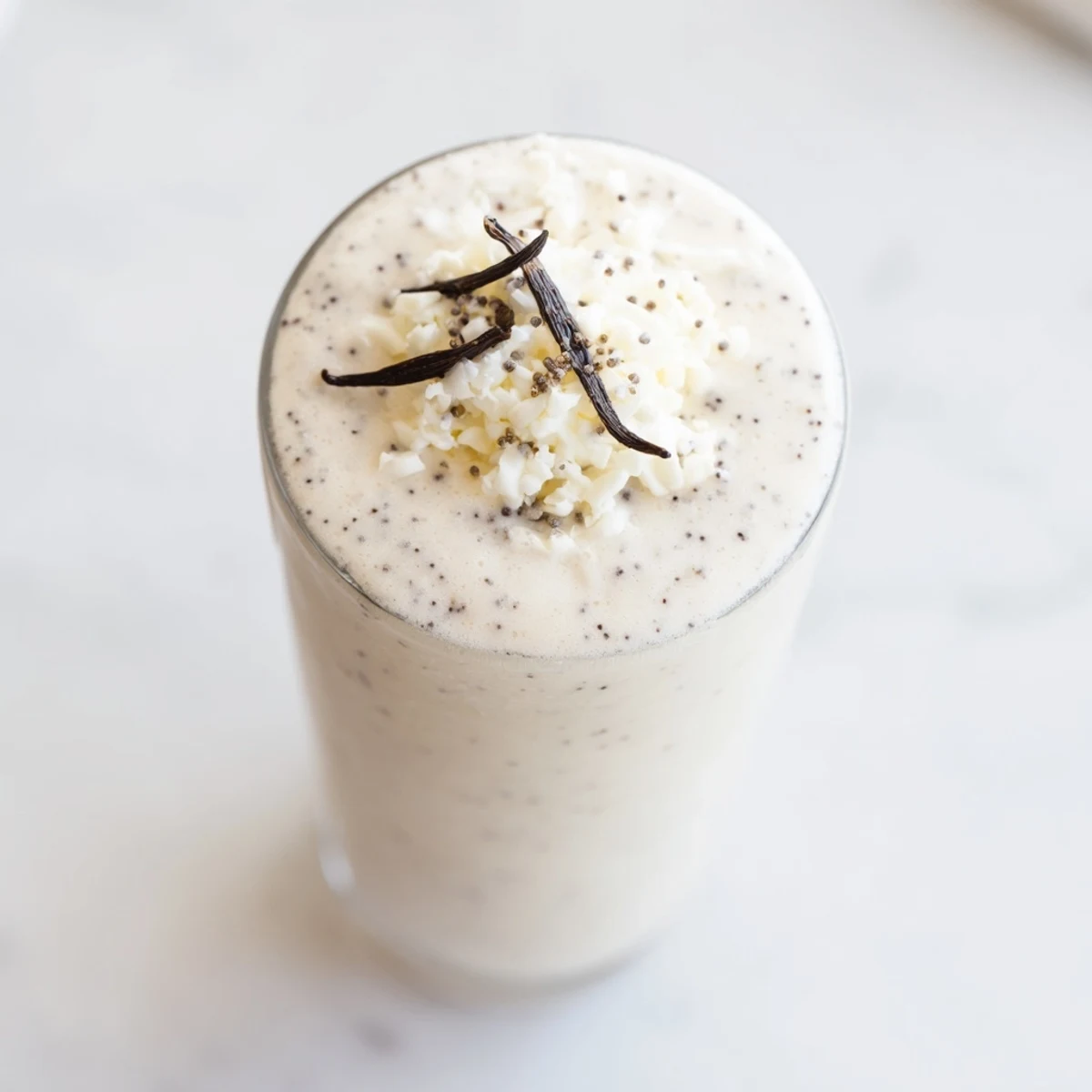 Two frosty glasses of Vanilla Bean Frappuccino being poured from a blender with creamy texture.