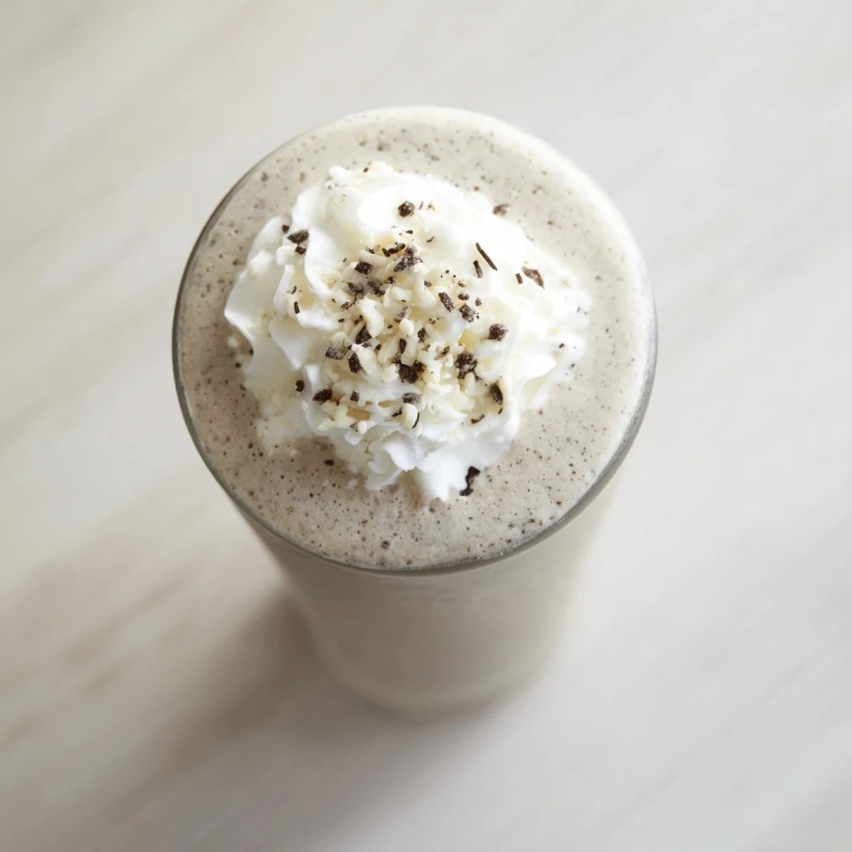 A tall glass of Vanilla Bean Frappuccino topped with whipped cream and white chocolate shavings.