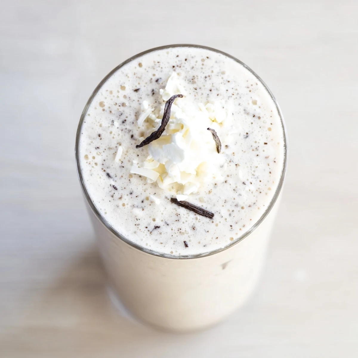 A close-up of Vanilla Bean Frappuccino in a tall glass, showing specks of real vanilla bean.