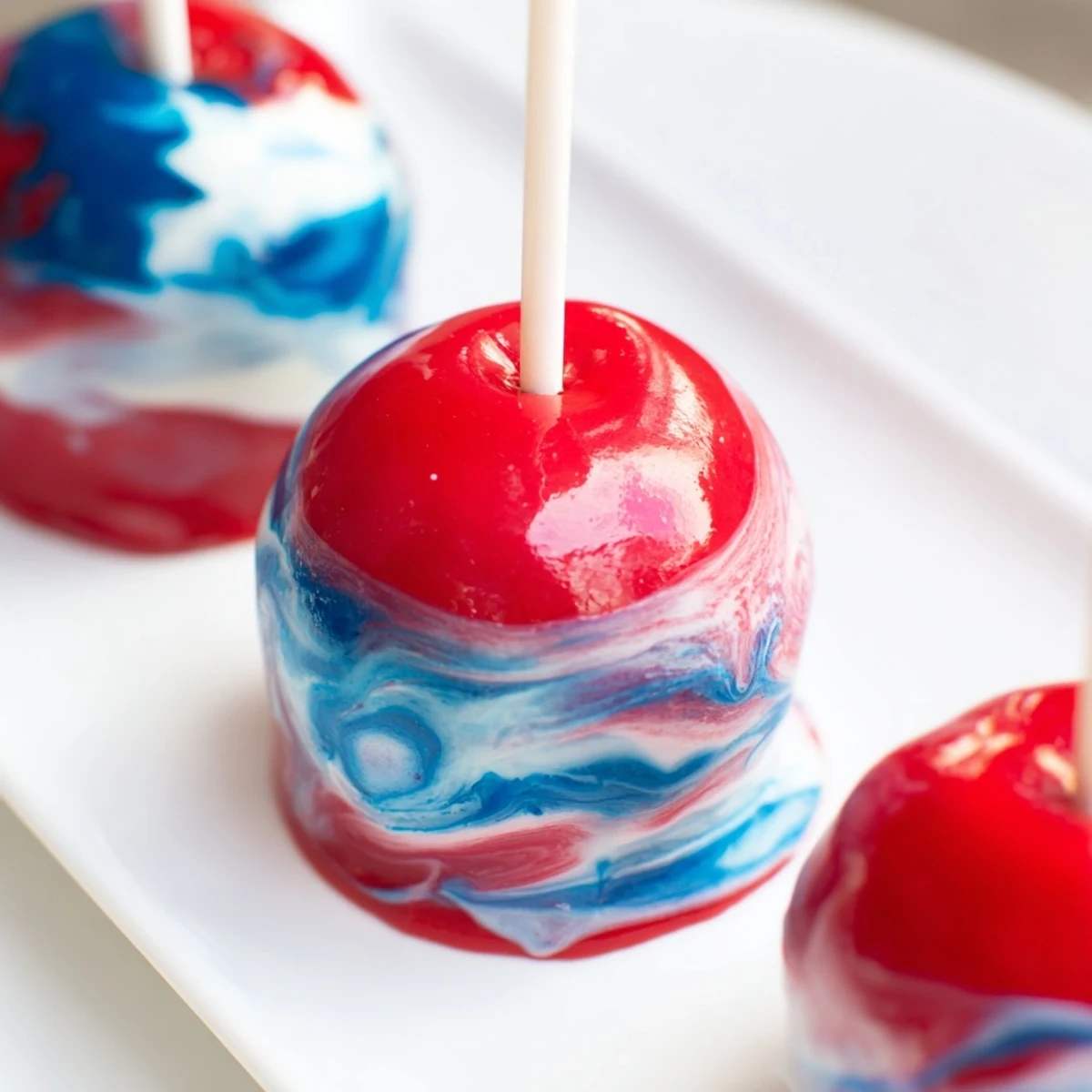 A close-up of marbled effect candy apples with vibrant red and blue swirls on a glossy candy shell.