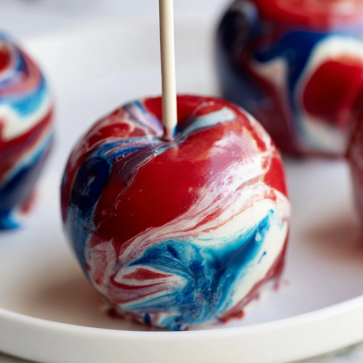 A hand dipping a marbled effect candy apple into a swirling candy syrup for a glossy finish.