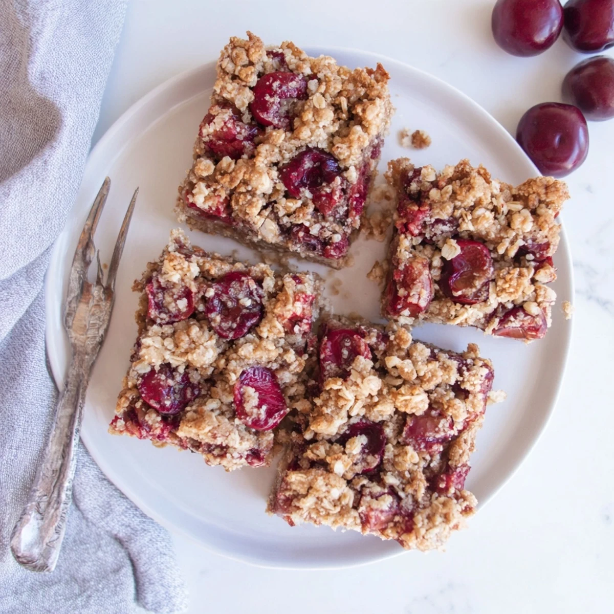 Close-up of Easy Tasty Cherry Crumble Bars cut into squares, showing a golden oat topping and a glossy red cherry filling.