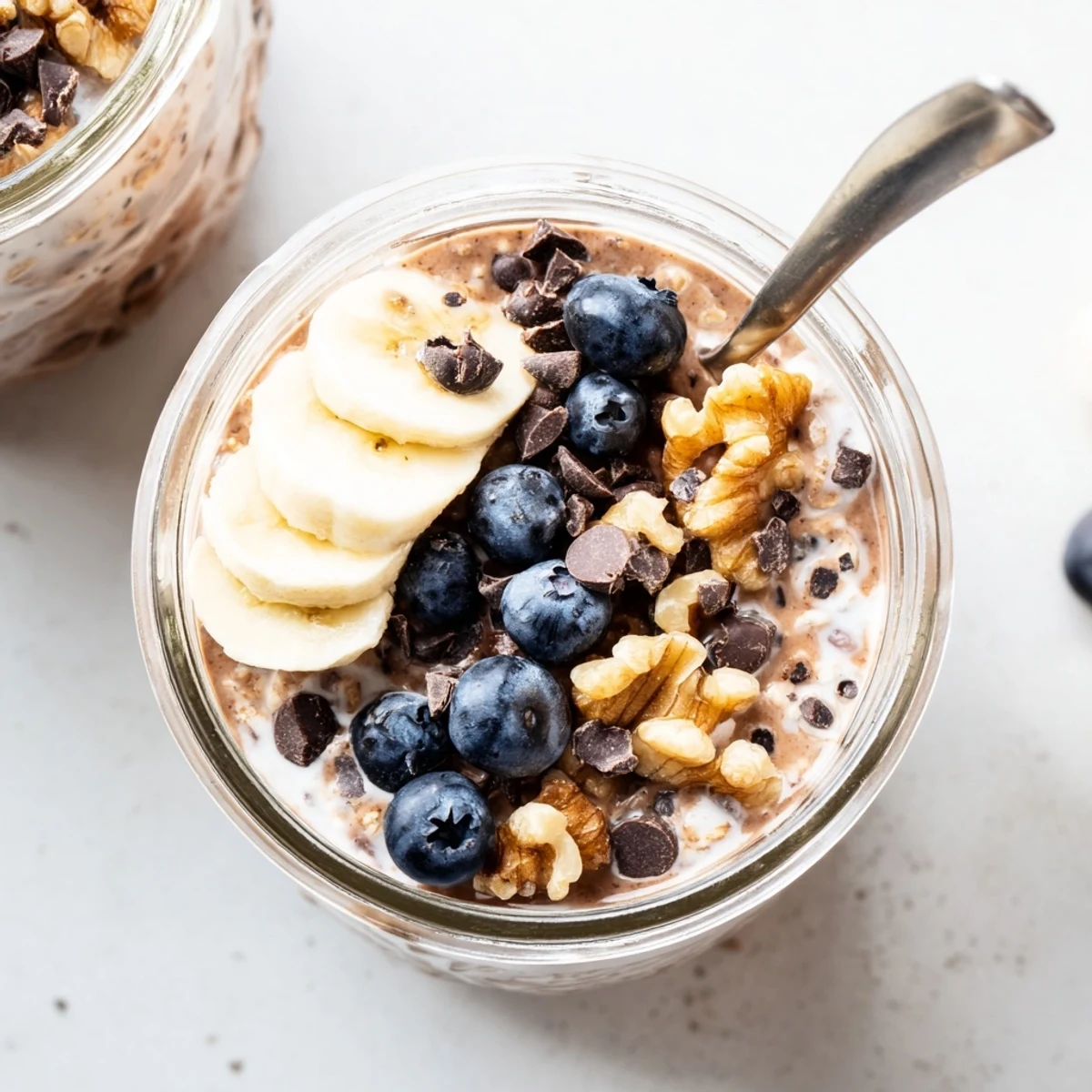 A textured bowl of Ultimate Healthy Chocolate Overnight Oats highlights its thick, chocolatey texture and toppings.