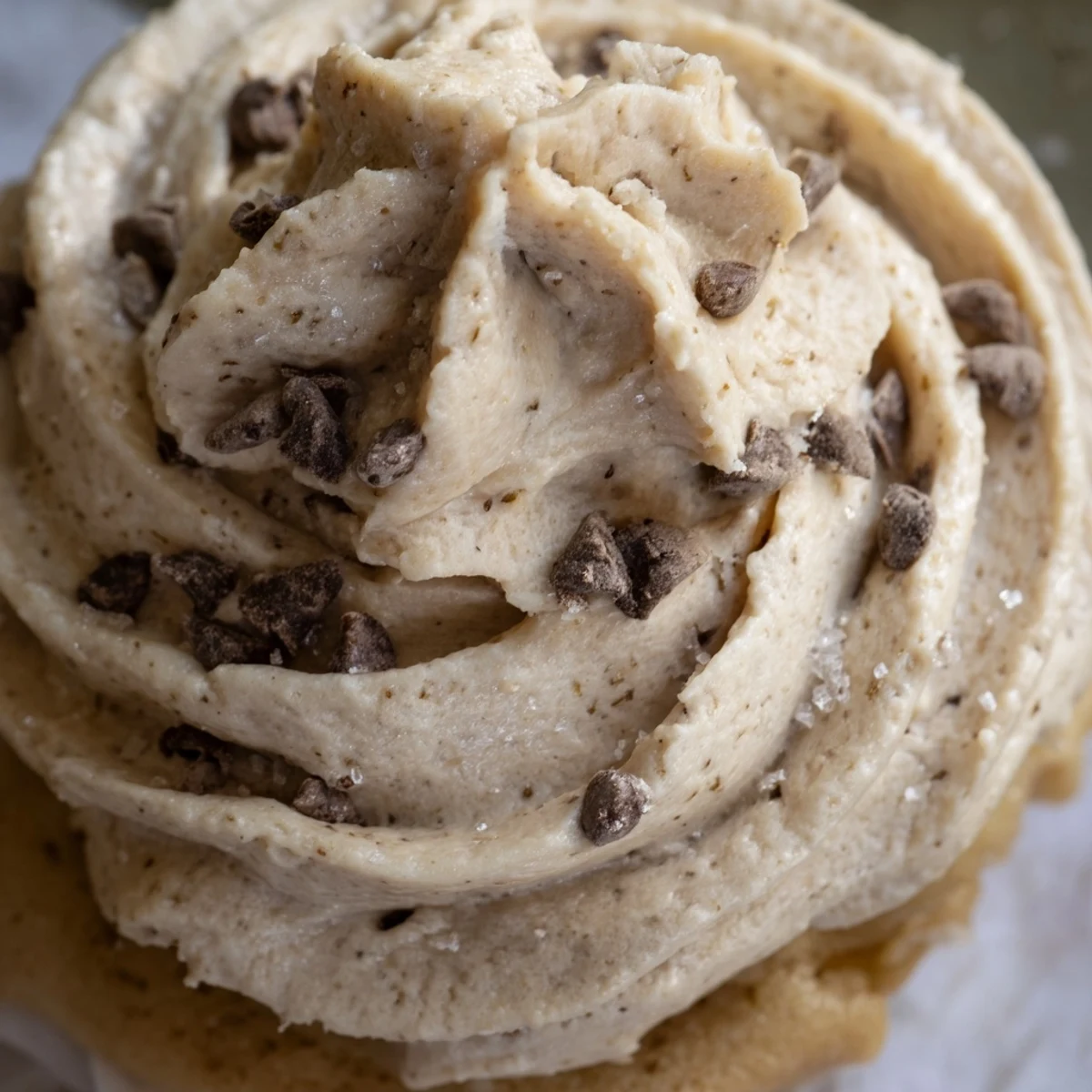 Creamy cookie dough frosting with mini chocolate chips spread on frosted cupcakes.