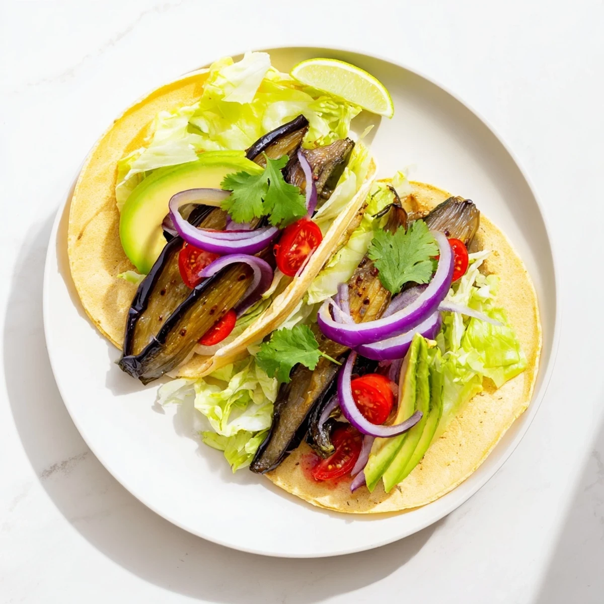 Plate of Charred Eggplant Tacos with char-marked eggplant strips and red onion, ready to serve for a vegan dinner.