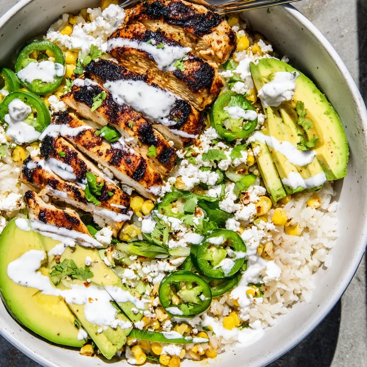 Grilled chicken and charred corn topped with crema in a Street Corn Chicken Bowl.