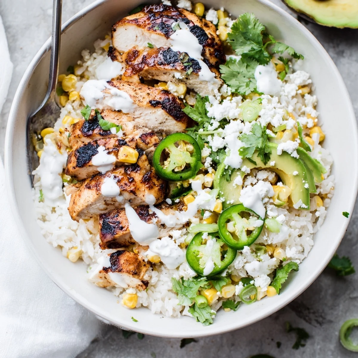 A hearty Street Corn Chicken Bowl served with lime wedges and spicy jalapeños.