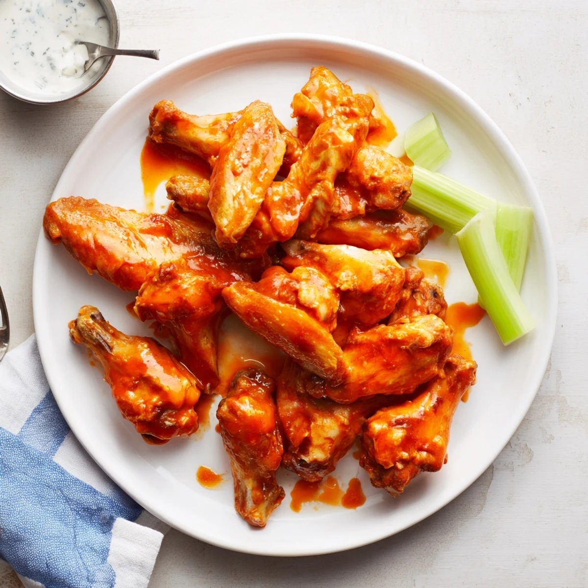 A platter of Crispy Smoked Buffalo Wings on a wooden board, showcasing smoky char marks and a side of blue cheese dip.