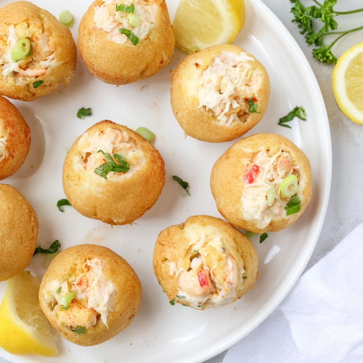 Golden-brown Cheesy Seafood Tortilla Bombs are served warm with a side of lemon wedges for a zesty appetizer.