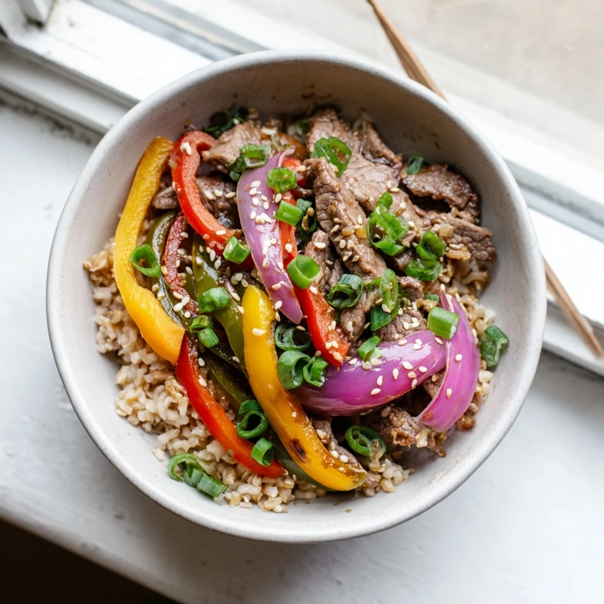 Sizzling Healthy Beef and Pepper Rice Bowl garnished with sesame seeds and fresh cilantro