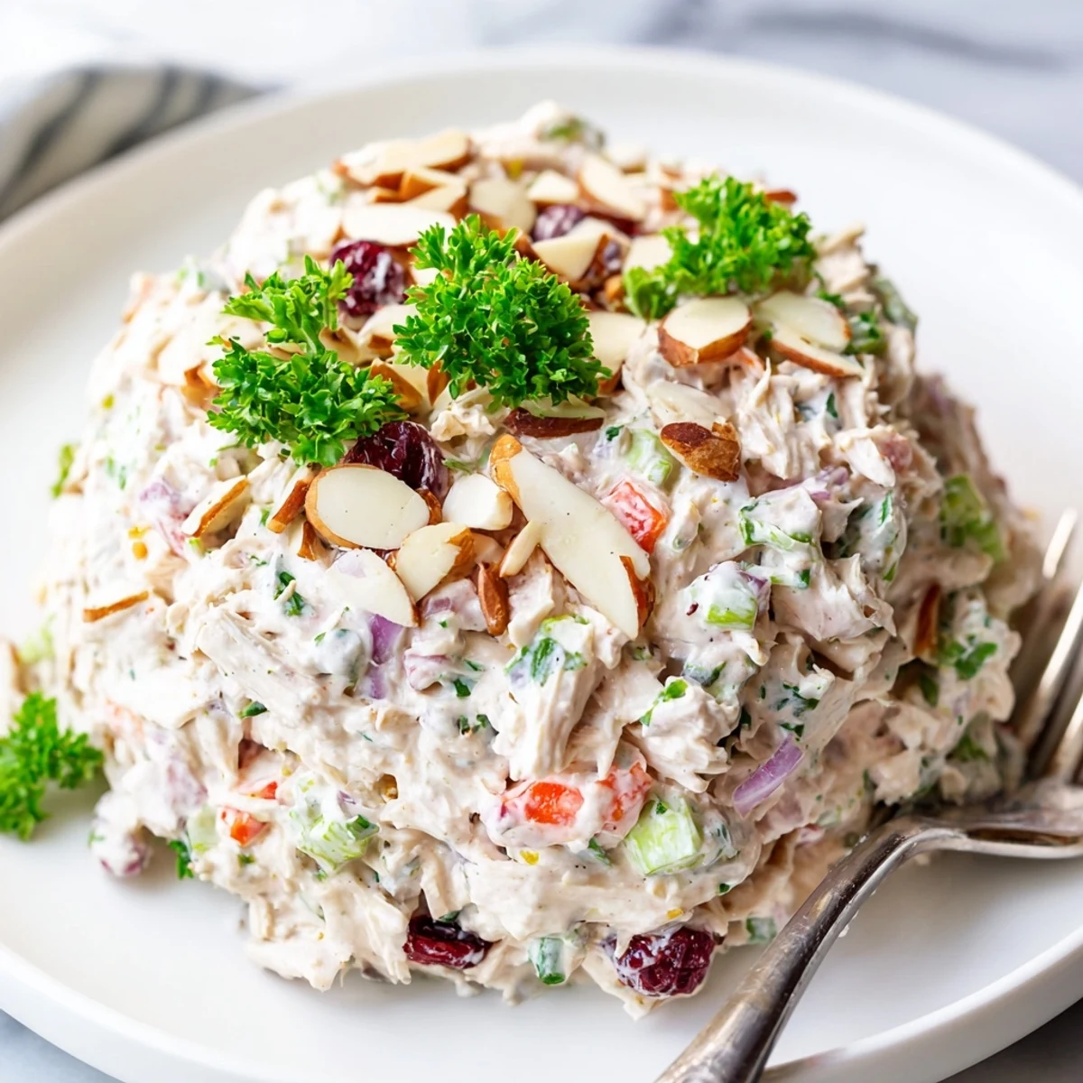 Healthy Greek yogurt rotisserie chicken salad served on bed of greens with crunchy almonds