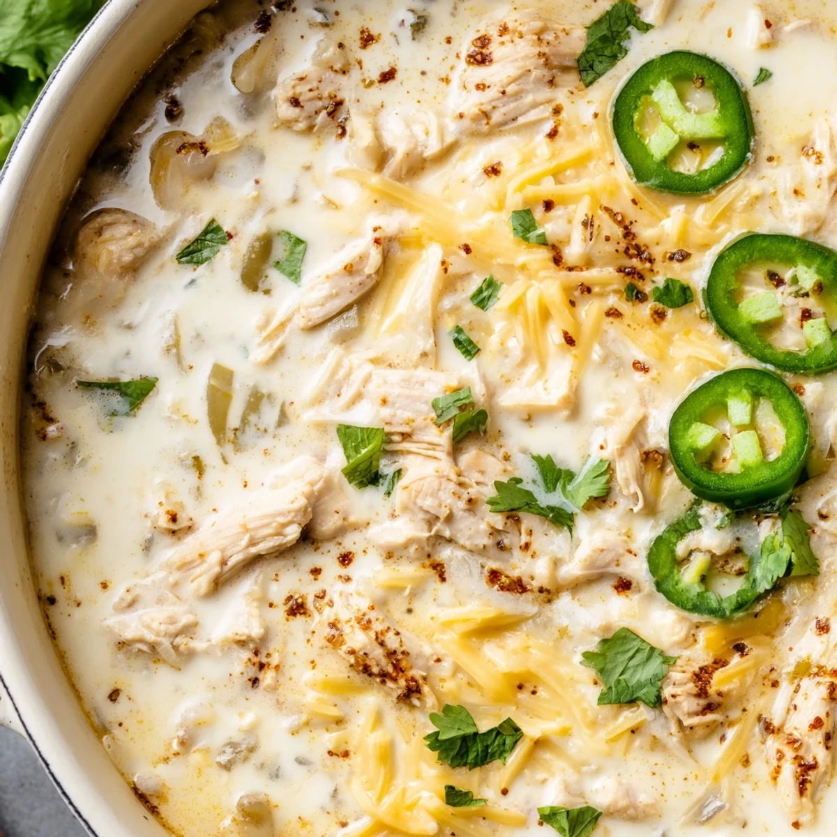 Creamy keto white chicken chili simmering with shredded chicken, green chiles, and melted Monterey Jack