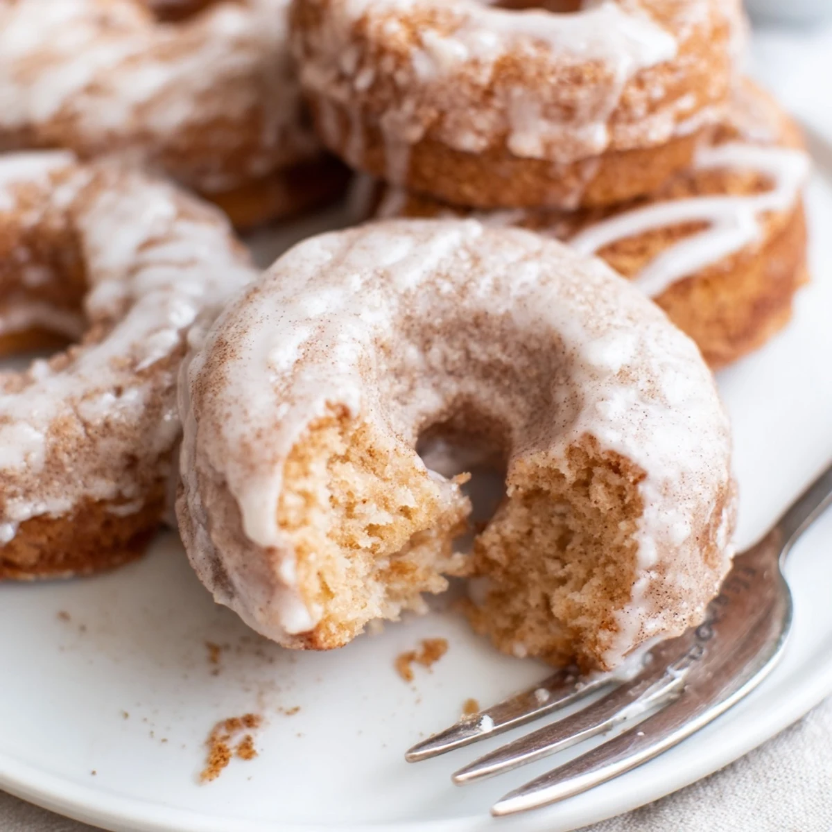 Golden brown pumpkin spice biscuit donuts coated in cinnamon sugar with sweet vanilla glaze drizzle