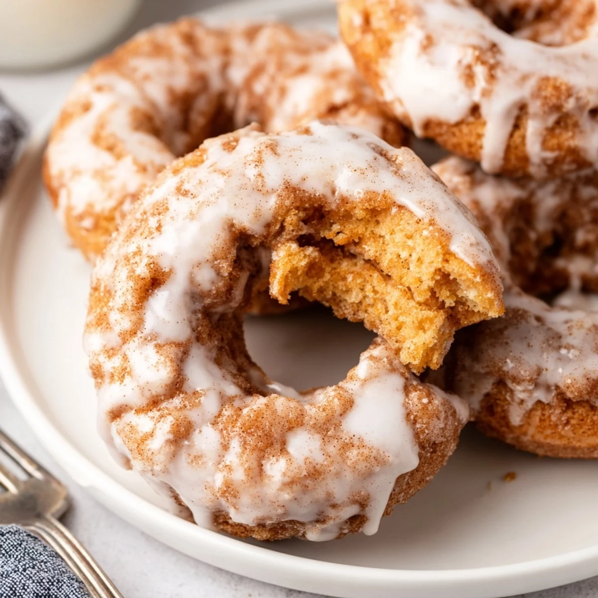 Fried pumpkin spice biscuit donuts sprinkled with cinnamon sugar and topped with creamy white glaze