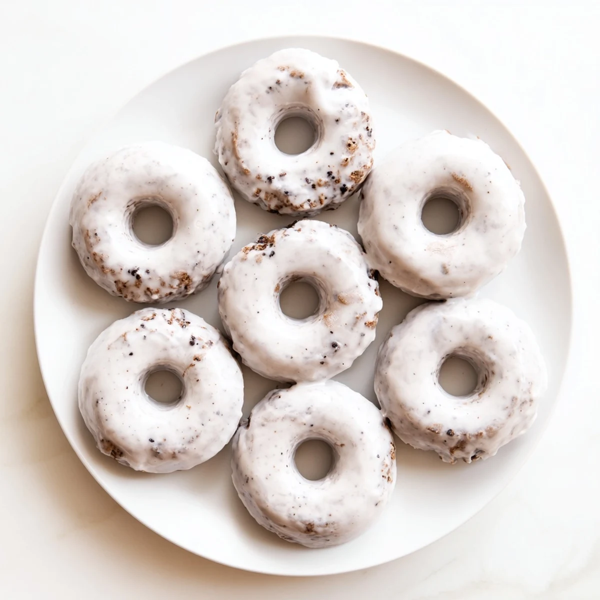 Close up of chewy Earl Grey mochi donuts topped with vanilla tea glaze and tea leaf specks