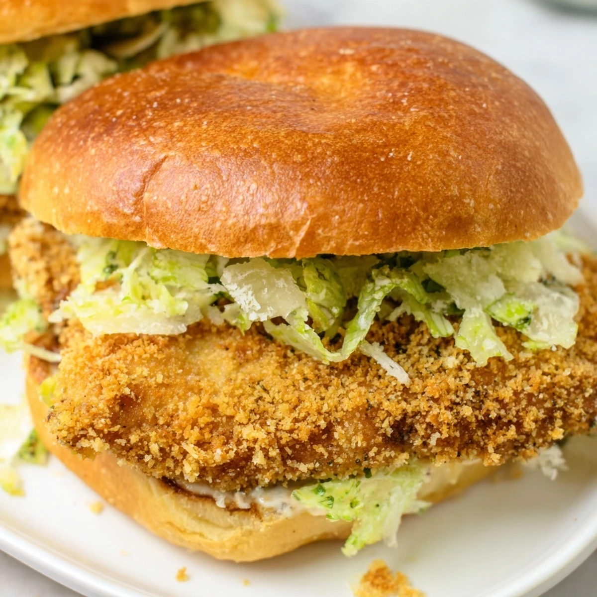 Homemade crispy chicken Caesar sandwich served on warm toasted bun with creamy Caesar sauce and shredded romaine lettuce