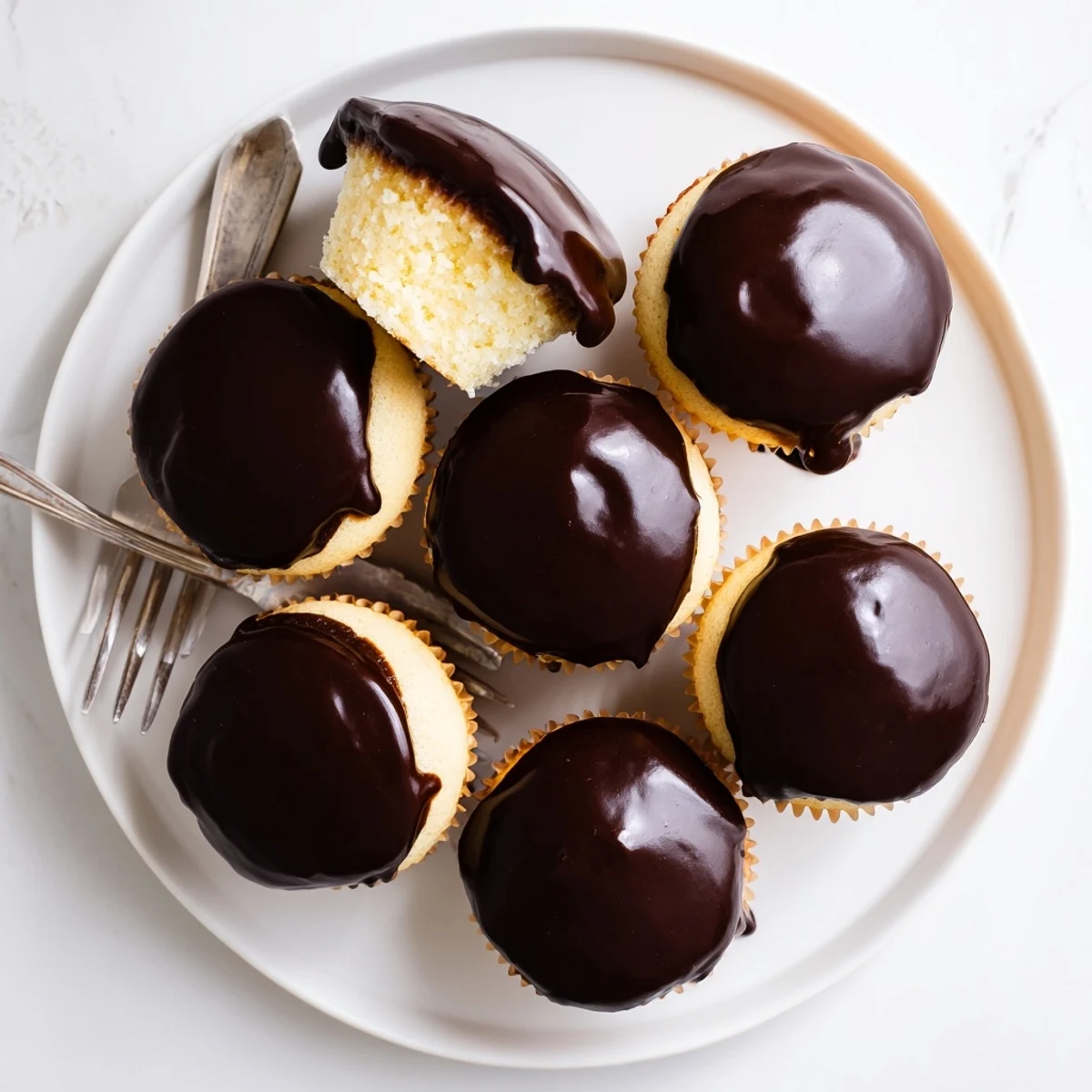 Homemade Boston cream pie cupcakes revealing layers of fluffy cake and smooth pastry cream filling