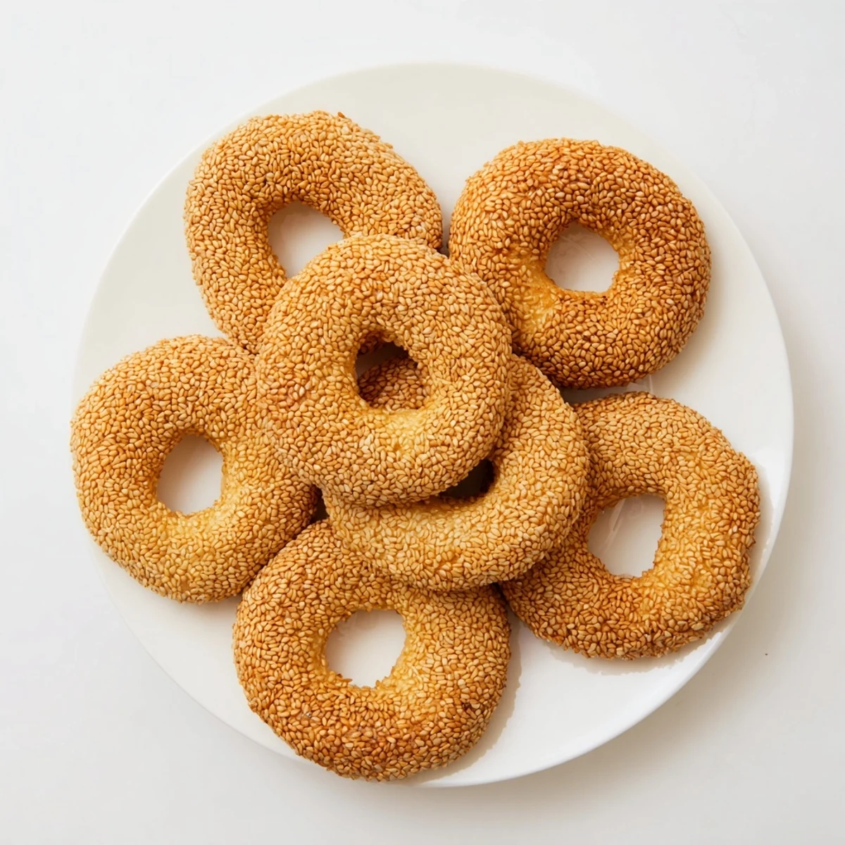 Mediterranean-style sesame bread rings coated in toasted seeds on a rustic wooden serving board