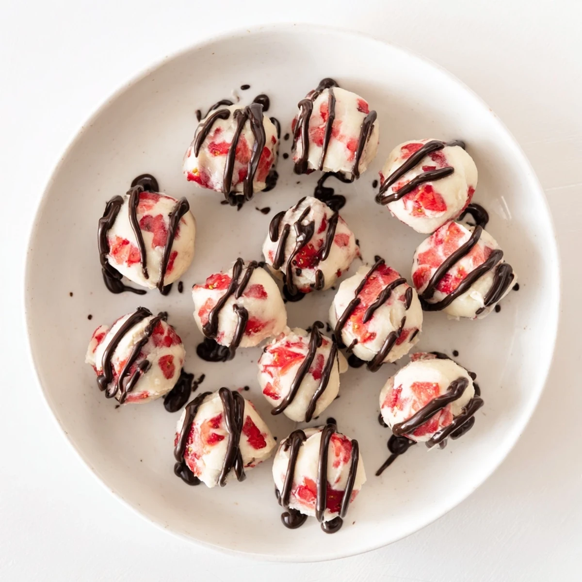 Fresh strawberry high protein yogurt bites arranged on a parchment lined baking sheet