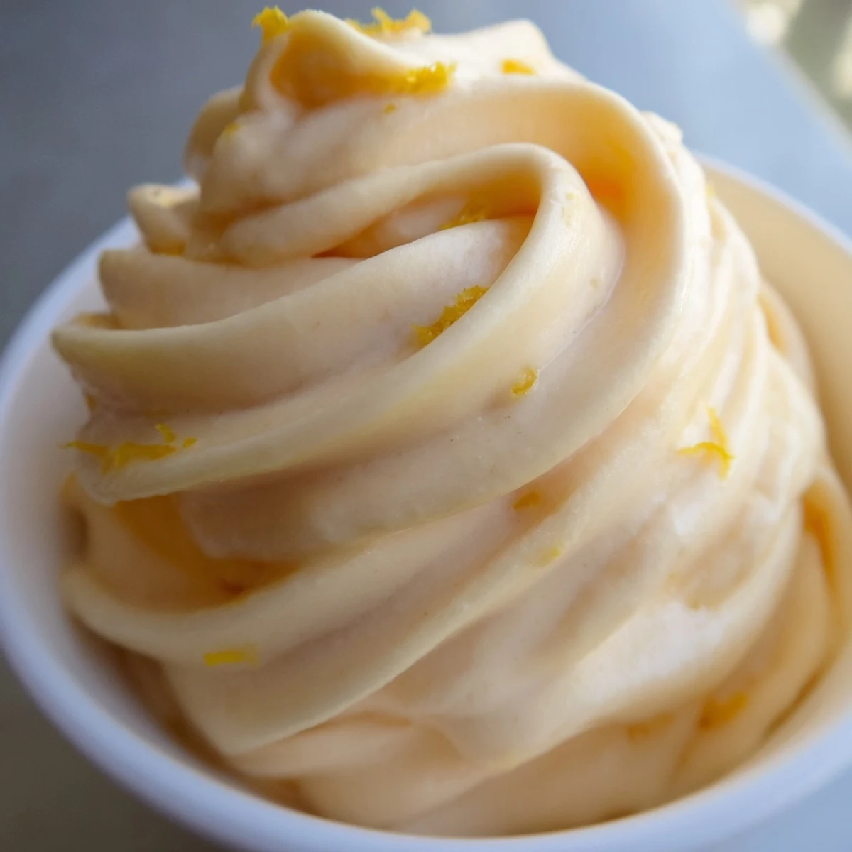 Vibrant orange frozen Dole Whip dessert served in a chilled bowl with pineapple chunks garnish