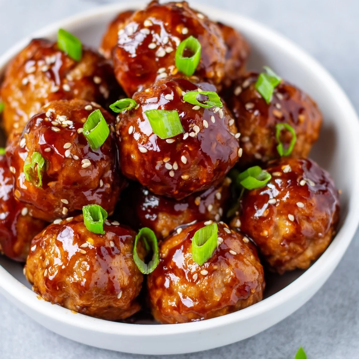 Japanese chicken meatballs simmered in thick teriyaki glaze garnished with fresh green onions