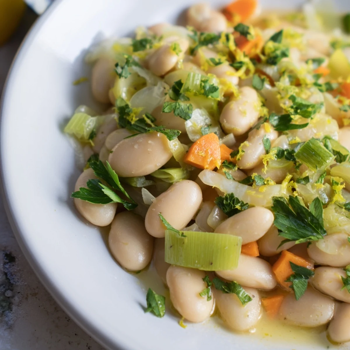 Creamy butter beans with leeks simmered in a skillet with fresh parsley garnish