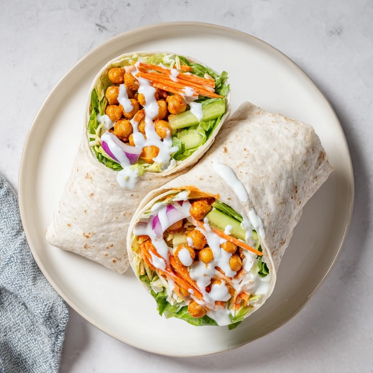 Vegetarian buffalo chickpea wraps featuring sautéed chickpeas in hot sauce with crunchy veggie toppings