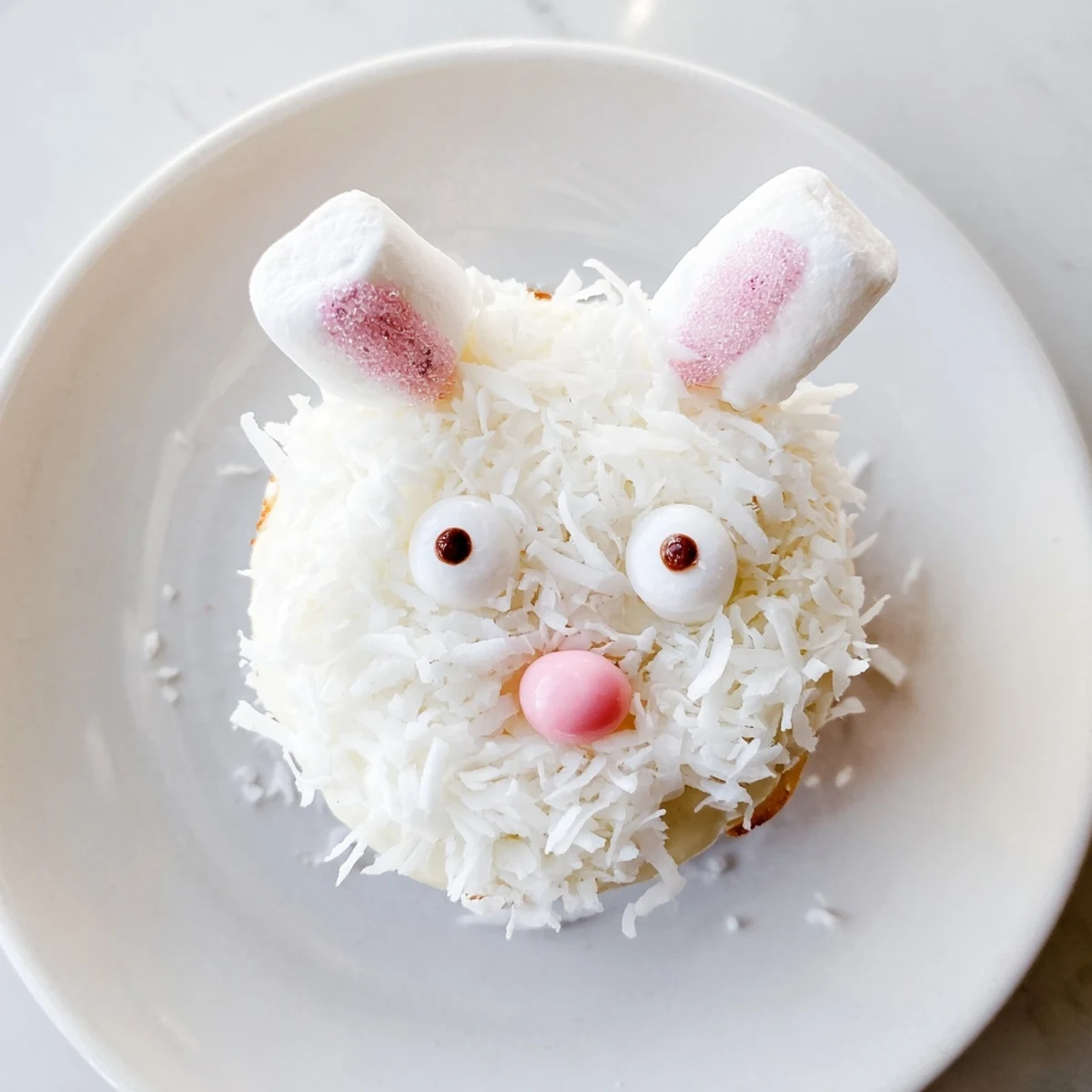 Easter bunny cupcakes with buttercream frosting, shredded coconut coating, and cute marshmallow ears sprinkled with pink sugar