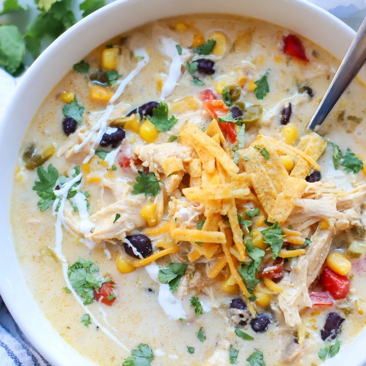 Comforting easy creamy chicken taco soup simmering in a pot with colorful vegetables and creamy broth, garnished with lime wedges