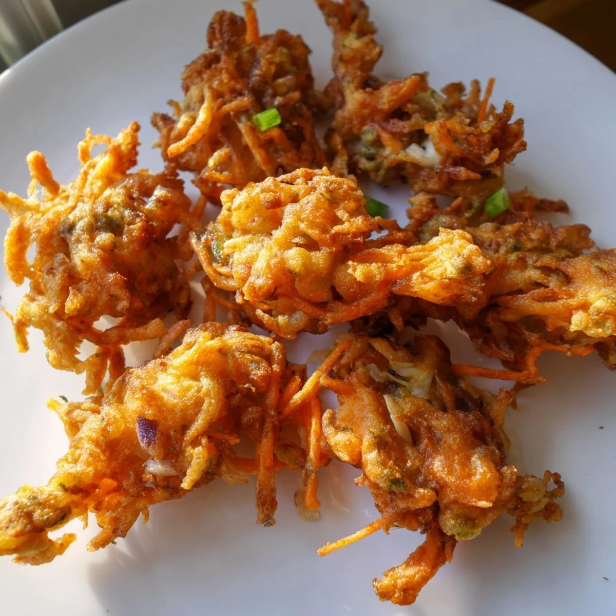 Golden crispy Ukoy Filipino shrimp fritters served with vinegar garlic dipping sauce on a white plate