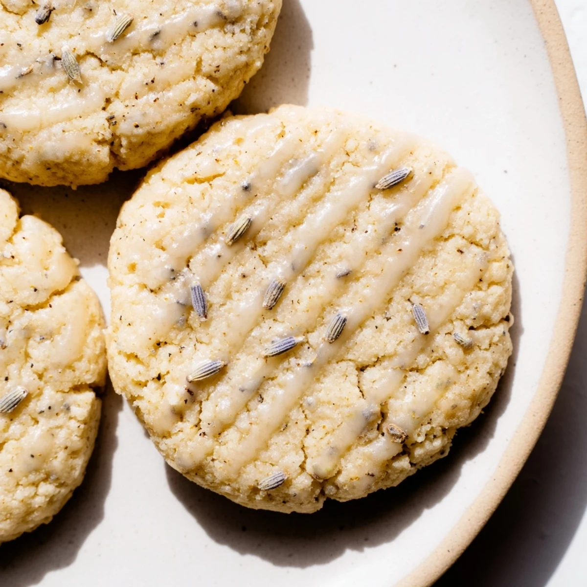 Soft Lemon Lavender Cookies with golden edges displayed on a rustic white ceramic plate