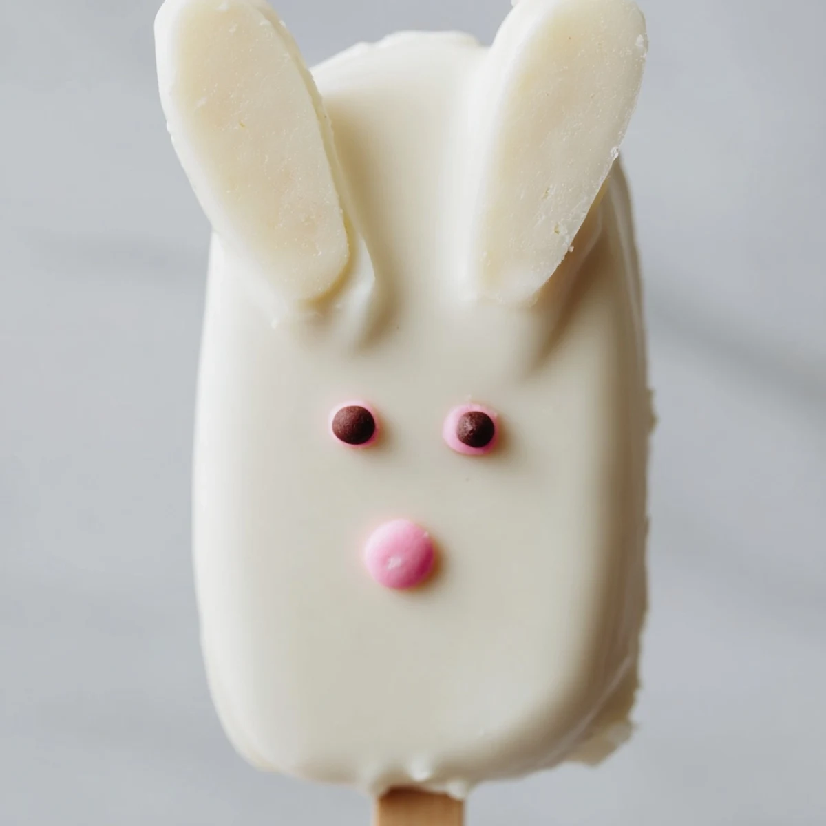 Creamy white chocolate bunny cakesicles decorated with sprinkles for festive Easter dessert