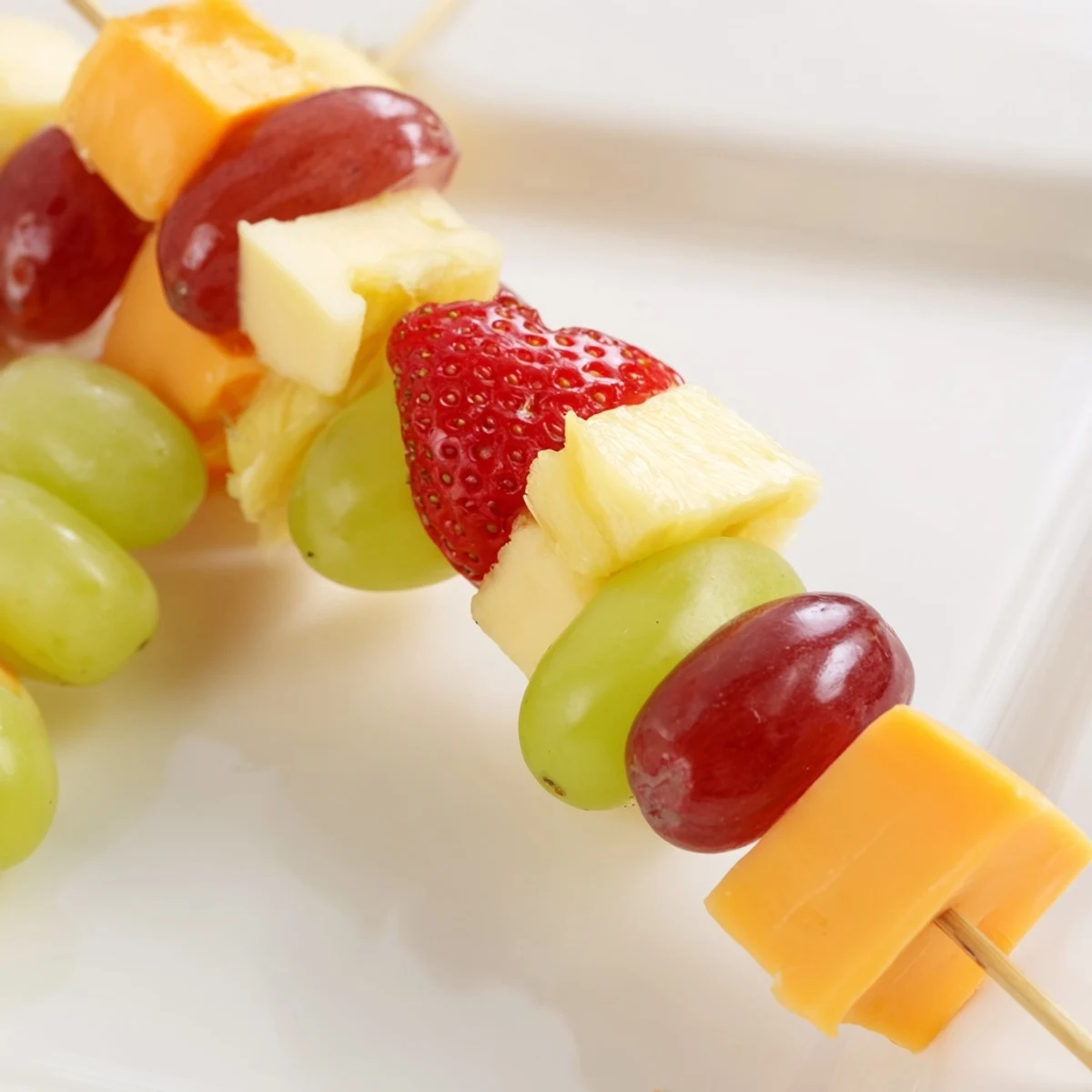 Fresh fruit and cheese kabobs featuring alternating cubes of Monterey Jack and seasonal fruits on wooden skewers