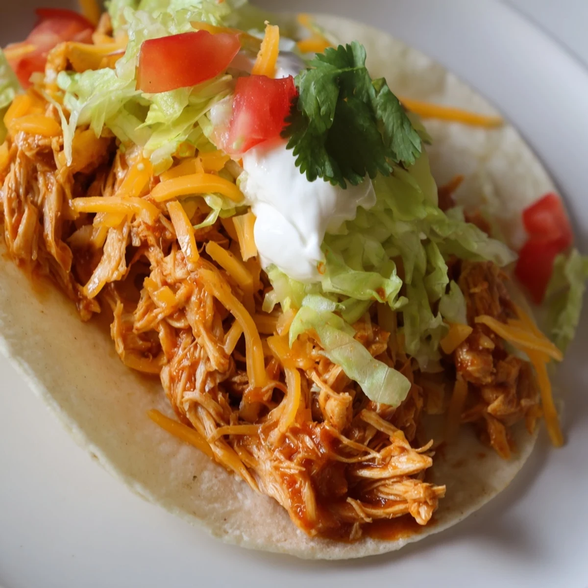 Juicy slow cooker shredded chicken tacos topped with melted cheese and fresh cilantro