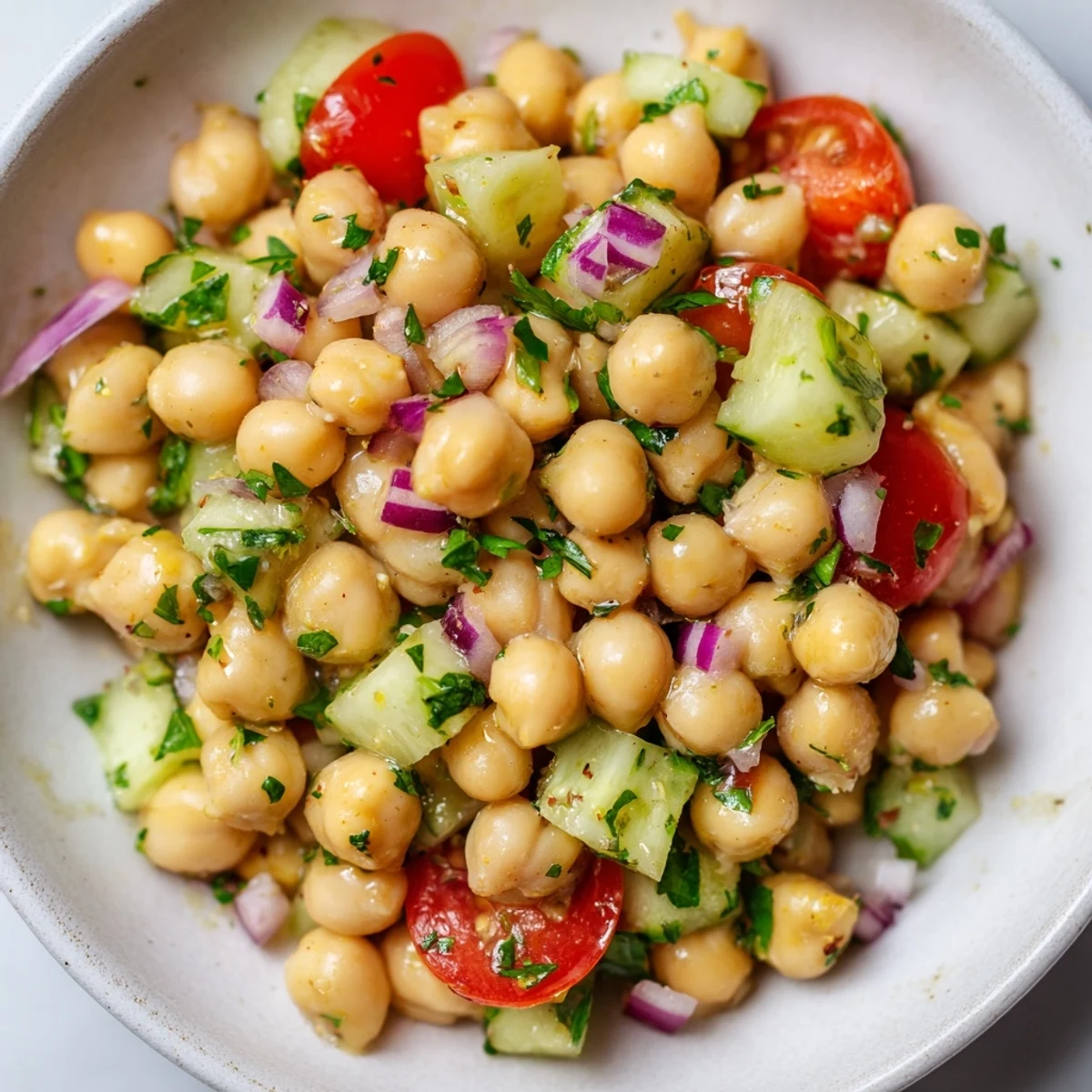 Crisp chickpea cucumber salad featuring ripe tomatoes, red onion, and bright parsley garnish