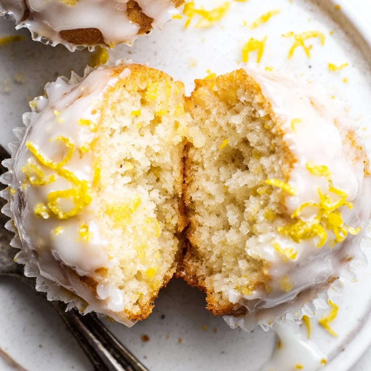 A stack of Glazed Lemon Ginger Muffins with bright zest and steam.