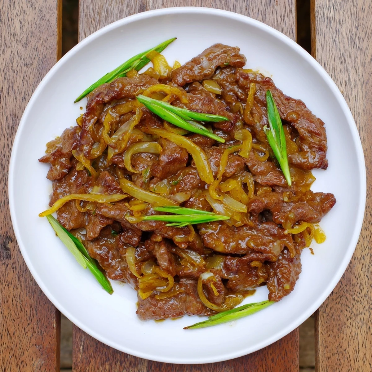 Golden brown crispy beef strips tossed with caramelized onions in a savory dark glaze
