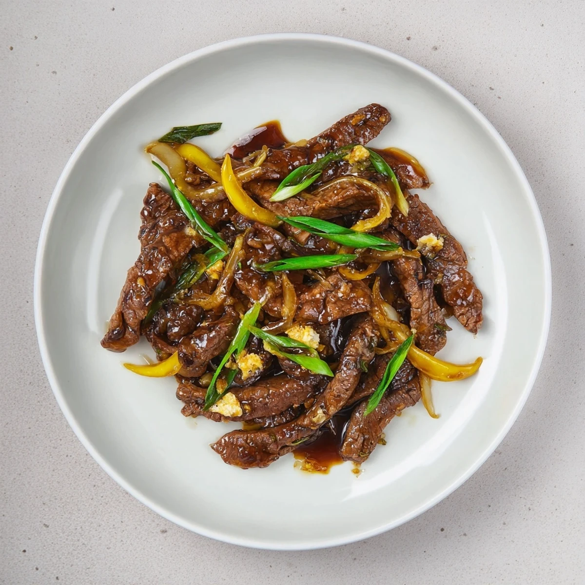 Plate of Chinese-style crispy beef and onion stir fry served over fluffy white steamed rice