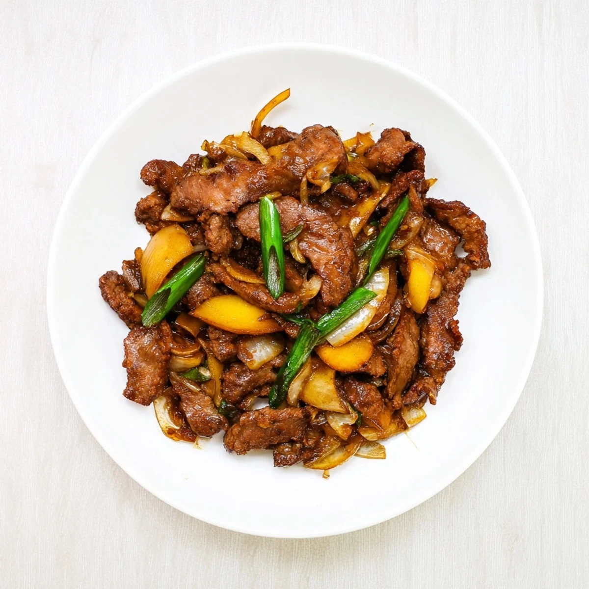 Sizzling wok filled with tender caramelized beef and onion stir fry garnished with fresh green onions