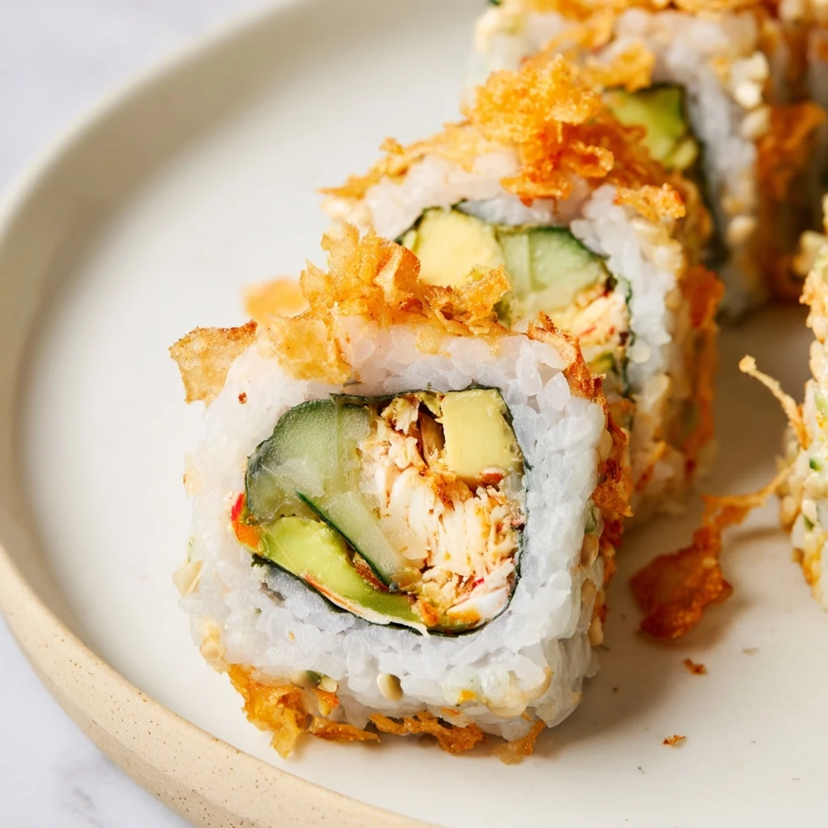 Close-up of sliced California Crunch Roll Sushi drizzled with spicy mayo and served with pickled ginger and wasabi