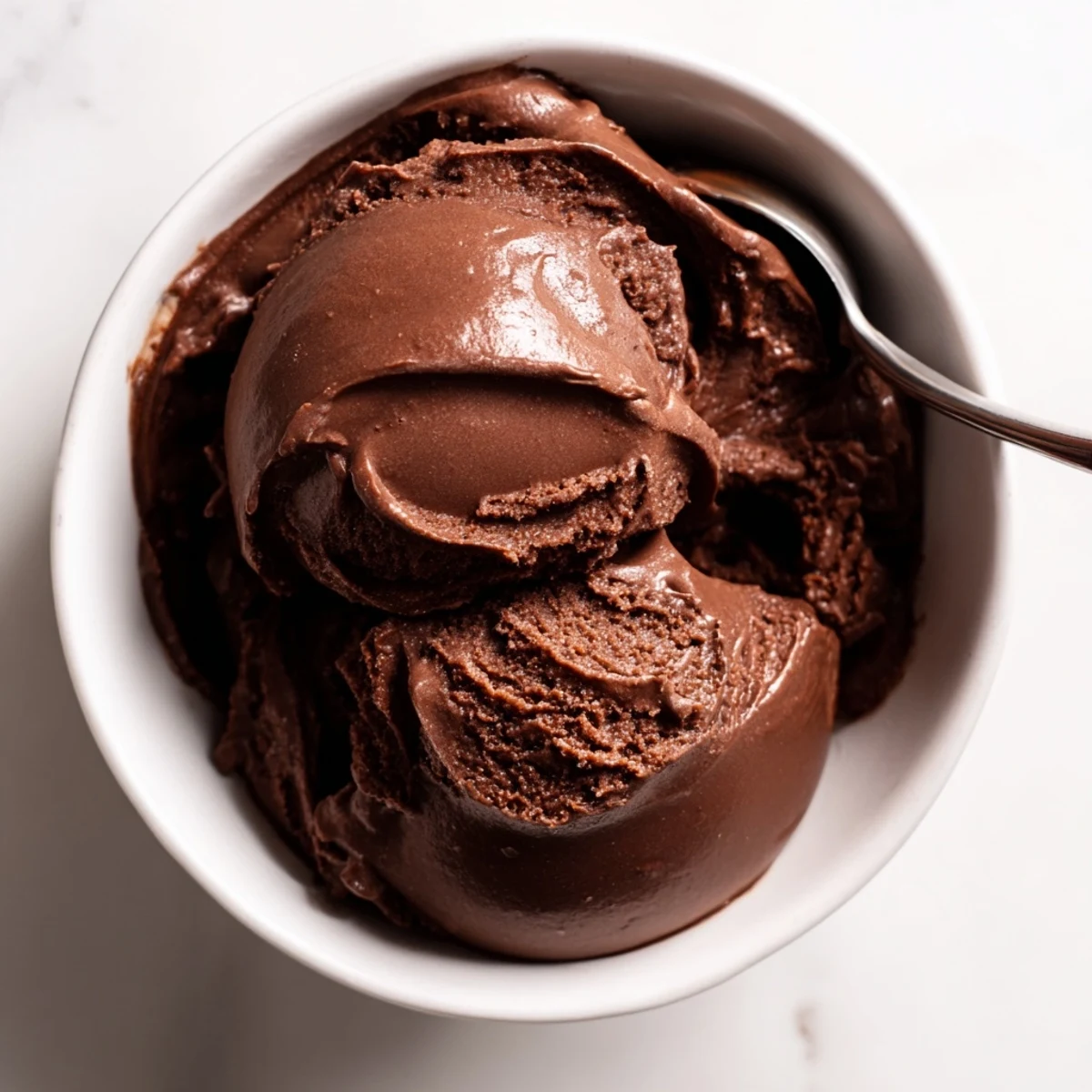 Creamy chocolate sourdough ice cream scooped into a bowl with drizzled chocolate sauce