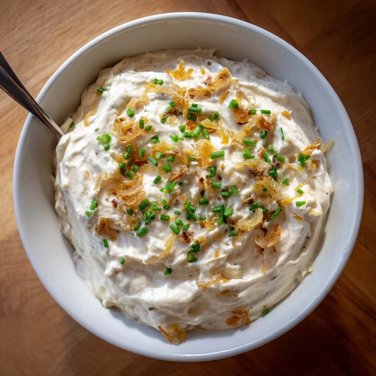 Creamy French onion dip topped with golden caramelized onions and fresh green onion garnish