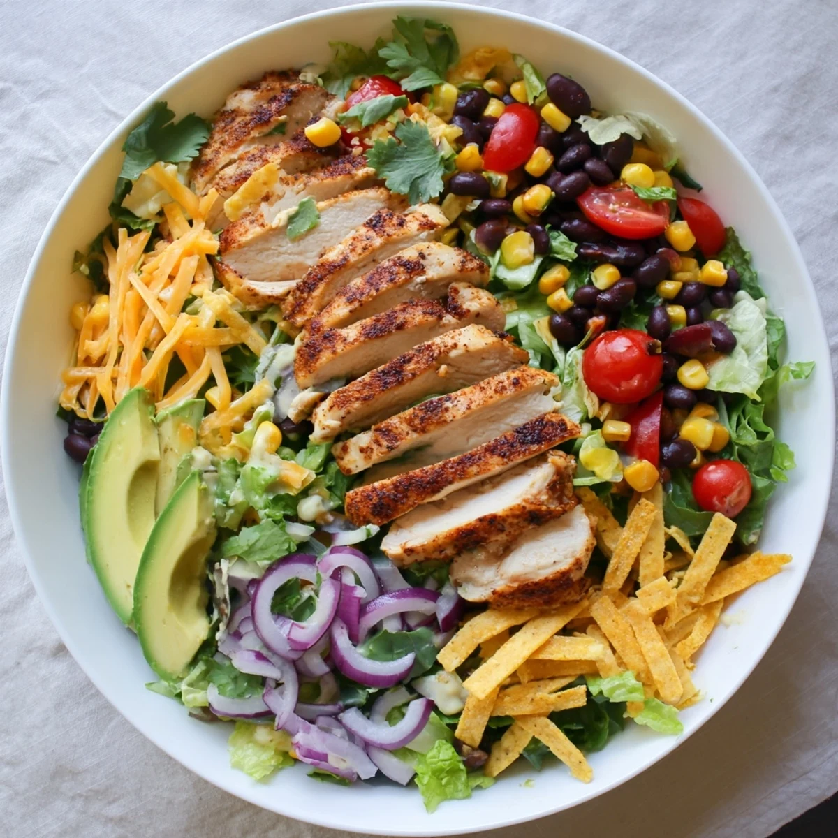 Vibrant Southwestern chicken salad featuring grilled spiced chicken over colorful greens with avocado black beans and tortilla strips