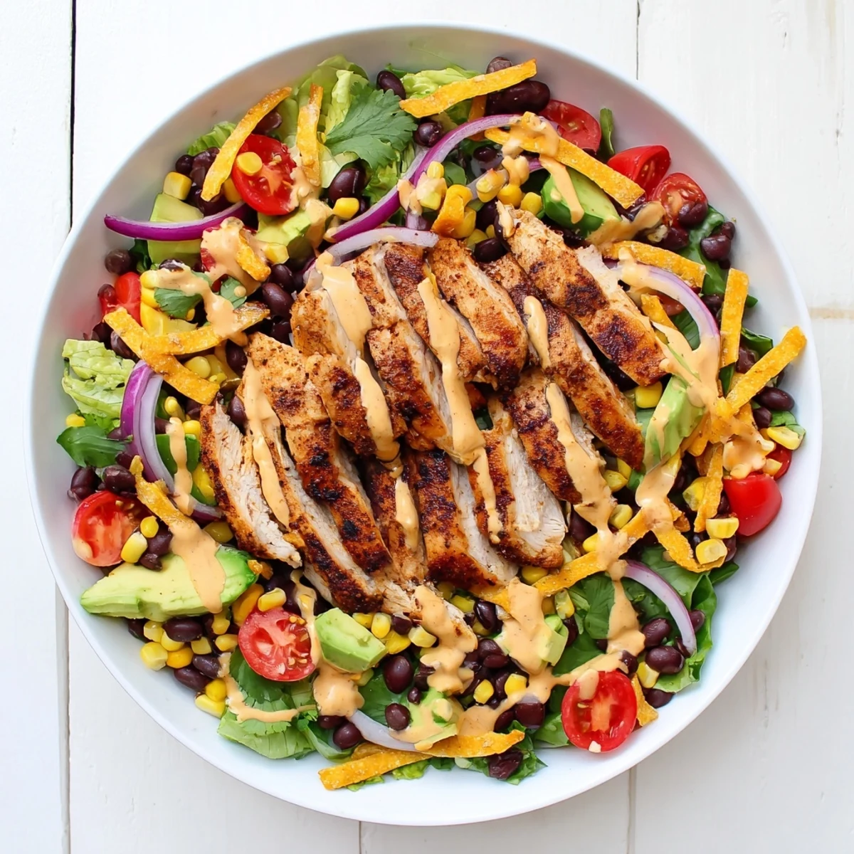 Ultimate Southwestern chicken salad recipe with warm seasoned sliced chicken atop crisp lettuce corn tomatoes and zesty lime dressing